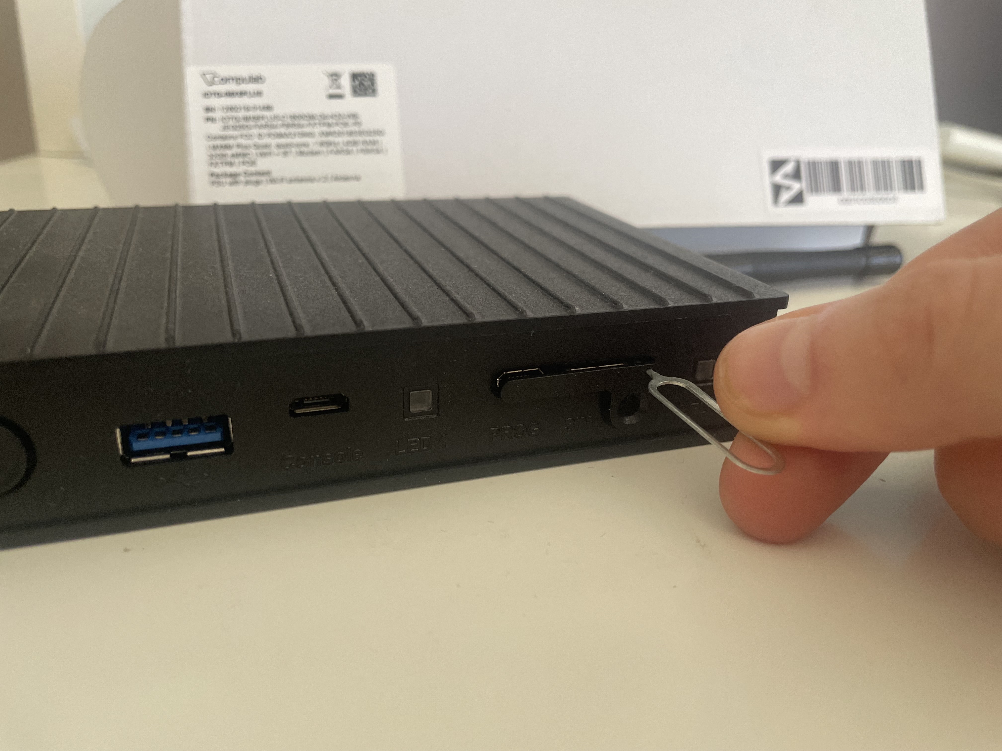 Using a SIM ejector pin to pop out the SIM card cover